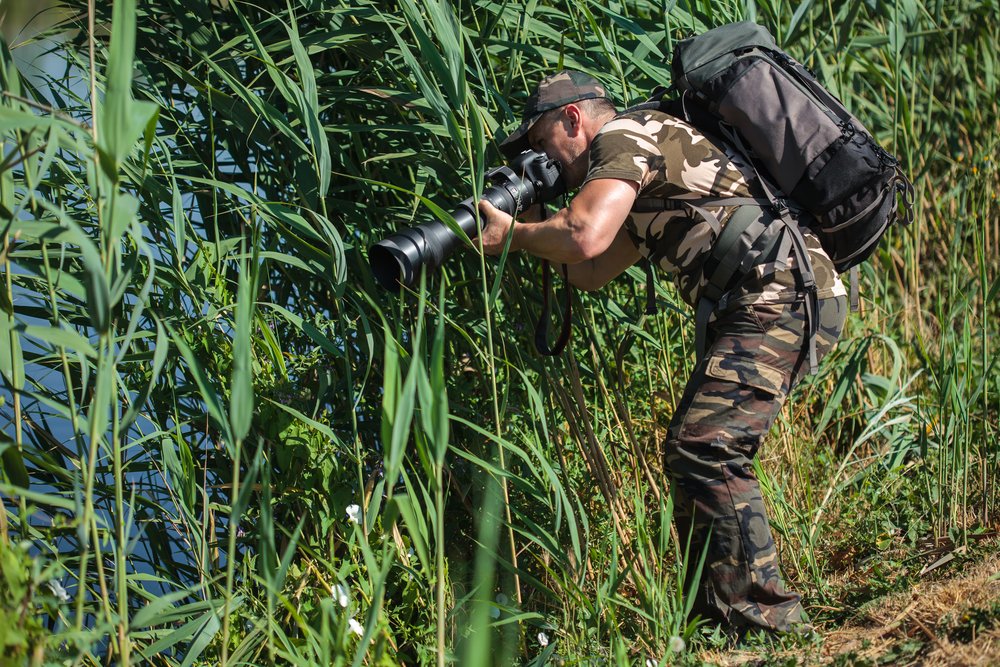 Professional nature and wildlife photographer with backpack and long lens
